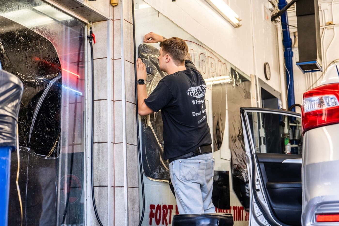 Technician working on a door window in the bay