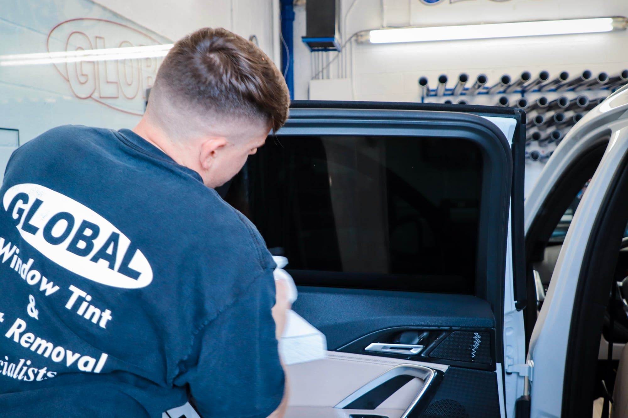 A Global Tint technician fitting window film to a vehicle door at the Fort Worth shop